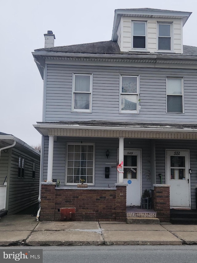 townhome / multi-family property featuring a shingled roof, a chimney, and covered porch