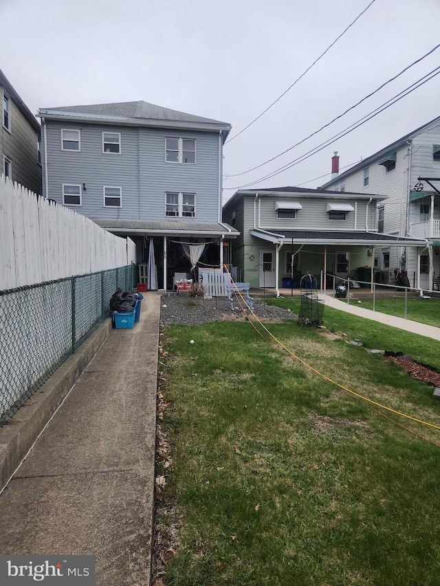 back of property with a yard and fence