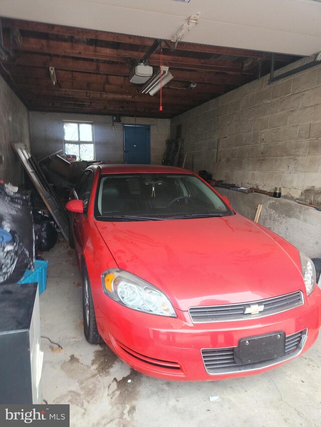 garage featuring a garage door opener, electric panel, and concrete block wall
