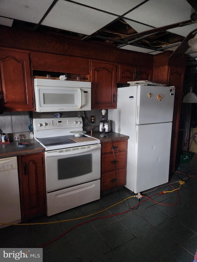 kitchen with dark tile patterned floors, dark countertops, and white appliances