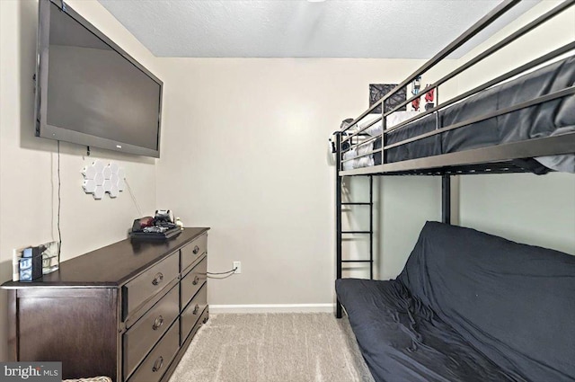 bedroom with baseboards, a textured ceiling, and light colored carpet