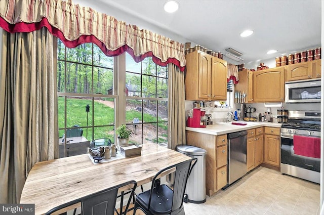 kitchen with appliances with stainless steel finishes, light countertops, light tile patterned floors, a sink, and recessed lighting