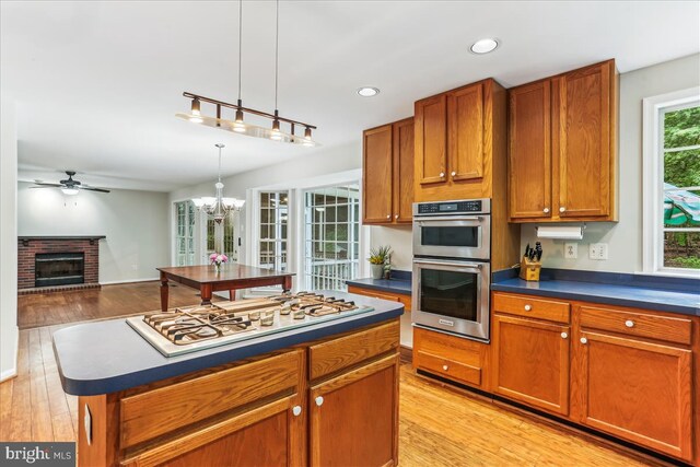 9409 Emory Grove Rd, Gaithersburg, MD 20877 - kitchen with dark countertops, white gas stovetop, stainless steel double oven, brown cabinets, and light wood finished floors