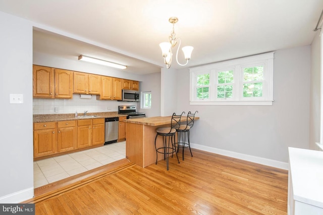 763 Humphreys Rd, Ardmore, PA 19003 - kitchen featuring appliances with stainless steel finishes, light wood-style flooring, a chandelier, baseboards, and a breakfast bar area