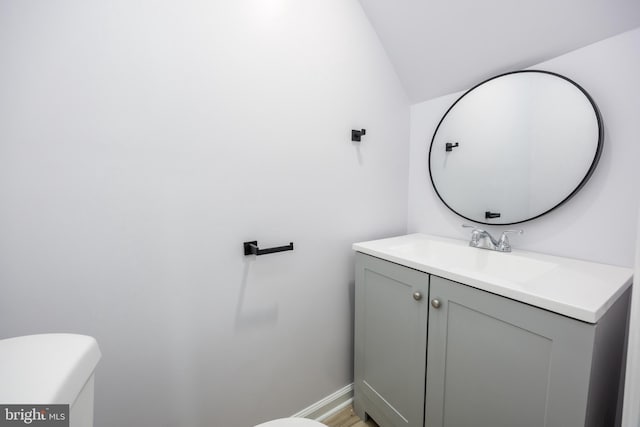 bathroom featuring toilet, vanity, and baseboards