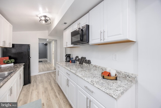 kitchen with white cabinets, black appliances, light wood-style floors, visible vents, and a sink