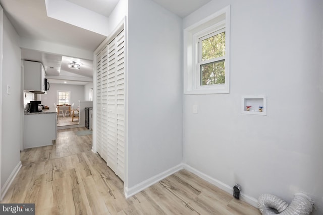 clothes washing area featuring light wood-type flooring, baseboards, and hookup for a washing machine