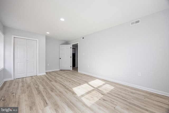 unfurnished bedroom featuring a closet, visible vents, light wood-type flooring, and baseboards