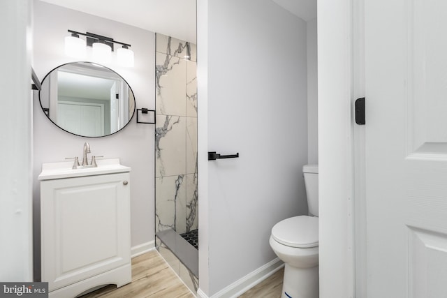 bathroom featuring vanity, baseboards, a marble finish shower, toilet, and wood finished floors