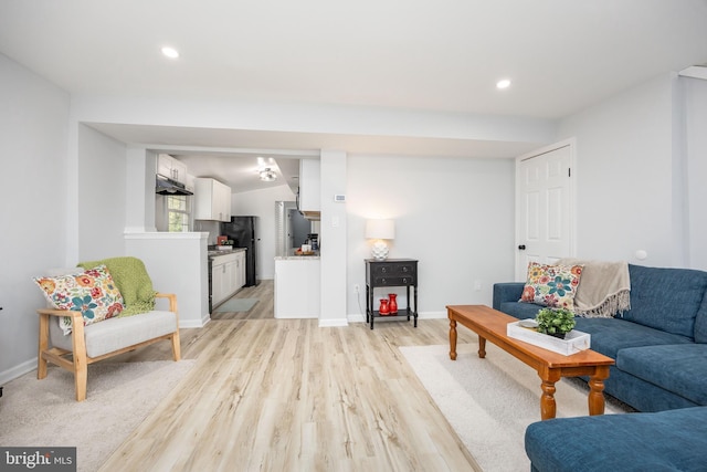 living area with baseboards, light wood-type flooring, and recessed lighting
