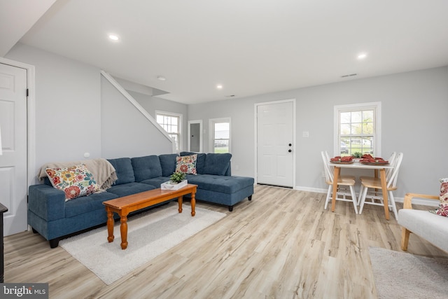 living area with recessed lighting, a wealth of natural light, stairway, and light wood-style floors