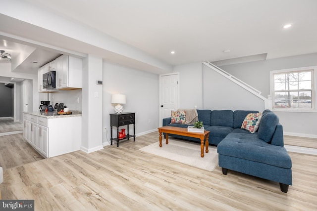 living area with light wood-style flooring, recessed lighting, baseboards, and stairs