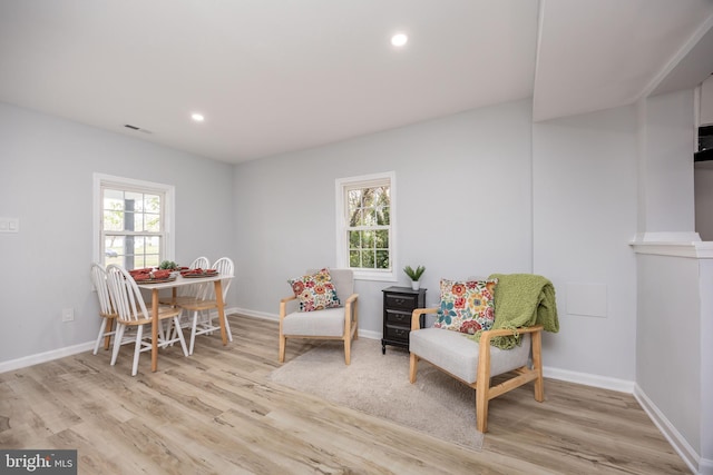 sitting room featuring visible vents, baseboards, light wood-type flooring, and a healthy amount of sunlight