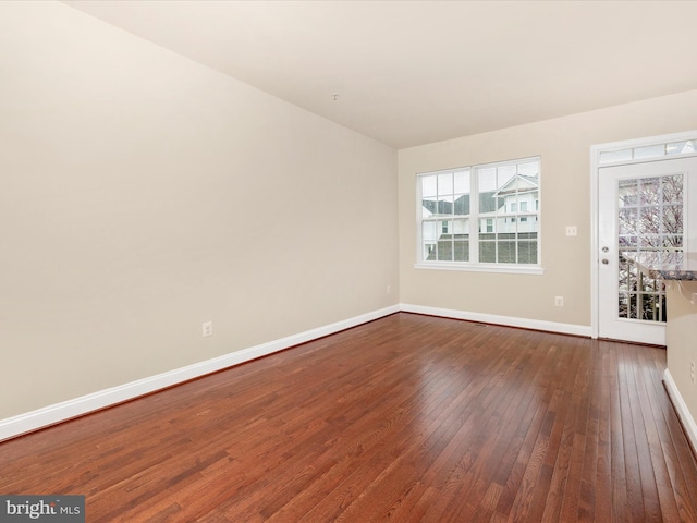 empty room featuring dark wood-type flooring and baseboards