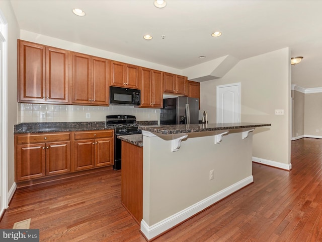 kitchen featuring dark wood-type flooring, backsplash, and black appliances
