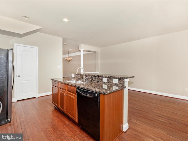 kitchen featuring dishwasher, a sink, freestanding refrigerator, an island with sink, and dark wood-style floors