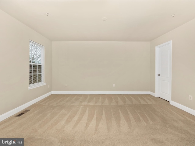 spare room with light carpet, visible vents, and baseboards