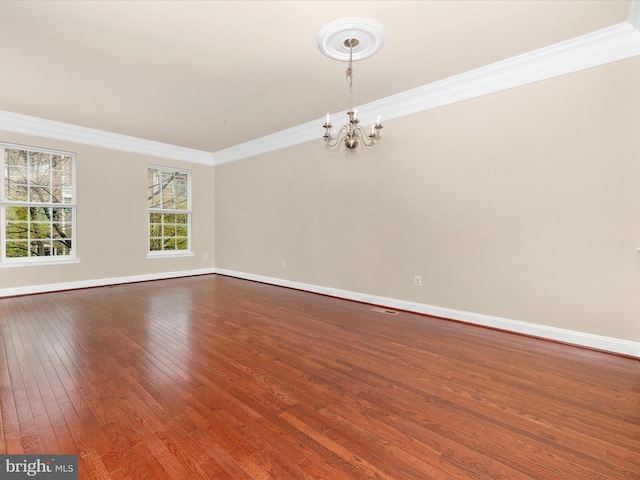 empty room featuring dark wood-style flooring, baseboards, a notable chandelier, and crown molding