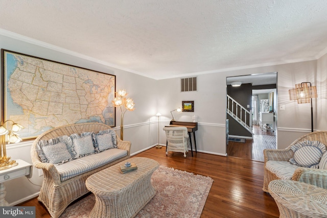 living area featuring a textured ceiling, hardwood / wood-style floors, visible vents, ornamental molding, and stairway