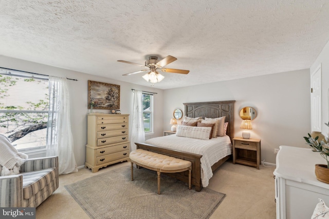 bedroom with light colored carpet, a ceiling fan, baseboards, and a textured ceiling