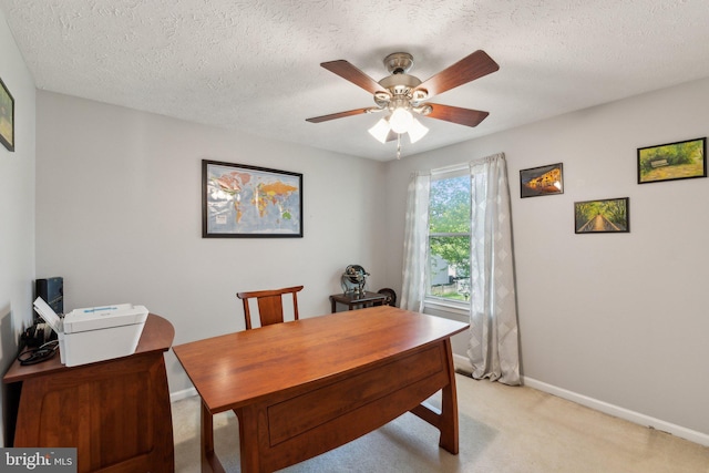office area featuring baseboards, ceiling fan, light carpet, and a textured ceiling
