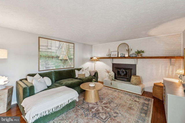 living room with a textured ceiling, brick wall, wood finished floors, and a fireplace