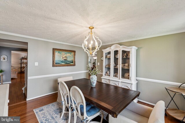 dining area featuring baseboards, a textured ceiling, wood finished floors, and a notable chandelier