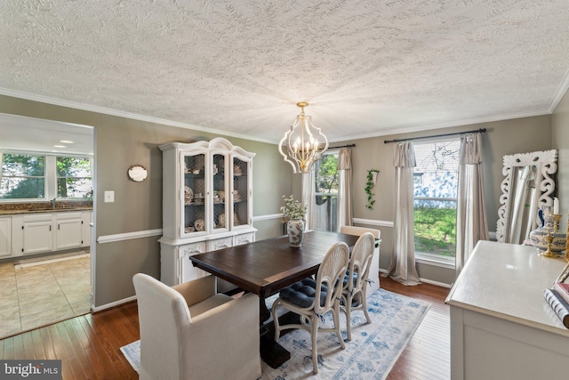 dining area featuring an inviting chandelier, crown molding, a healthy amount of sunlight, and hardwood / wood-style flooring
