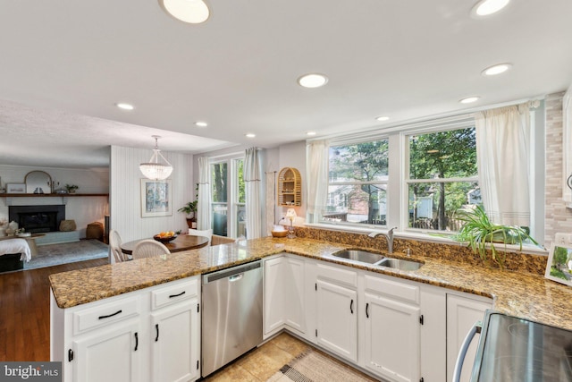 kitchen featuring light stone countertops, dishwasher, a sink, a peninsula, and white cabinetry