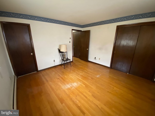 2060 Mahantongo St, Pottsville, PA 17901 - unfurnished bedroom featuring a baseboard radiator, light wood-style floors, baseboards, and multiple closets