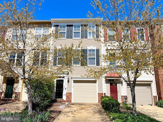 view of property featuring an attached garage, brick siding, and driveway
