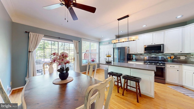kitchen featuring a center island, dark countertops, decorative backsplash, stainless steel appliances, and ornamental molding