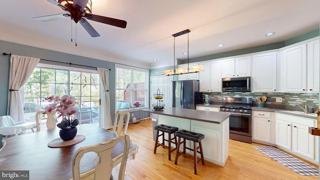 kitchen featuring a center island, a sink, dark countertops, decorative backsplash, and appliances with stainless steel finishes
