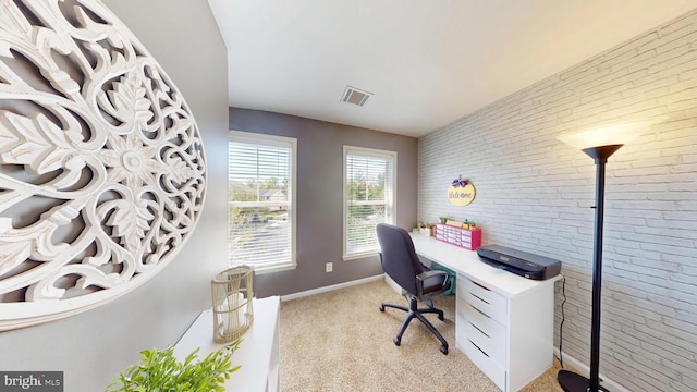 office with baseboards, visible vents, light colored carpet, and brick wall