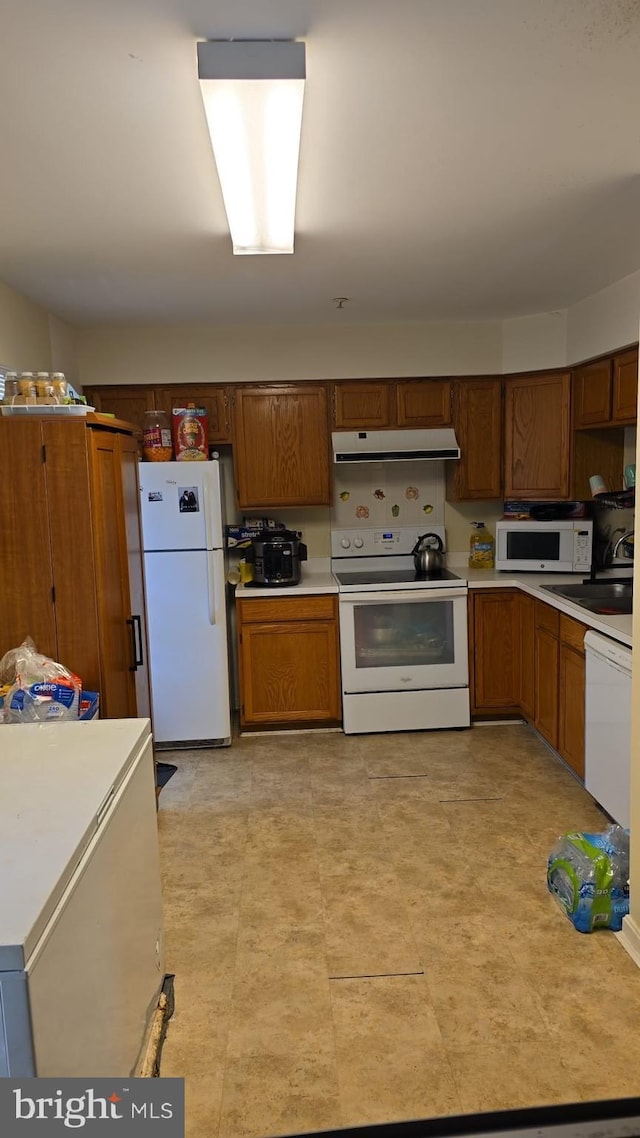 kitchen with white appliances, extractor fan, light countertops, and brown cabinetry
