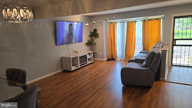 living room with baseboards, a chandelier, and wood finished floors