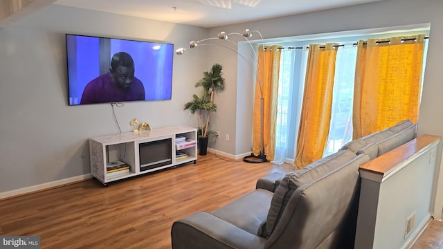 living area with wood finished floors, baseboards, and visible vents