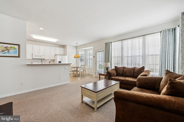 living area featuring light colored carpet and baseboards