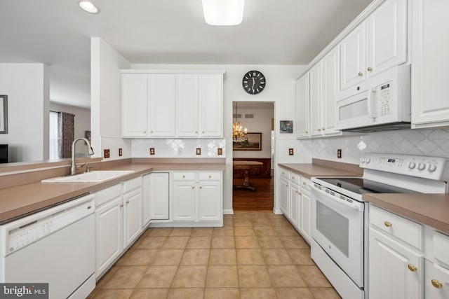kitchen with white cabinets, backsplash, a sink, and white appliances