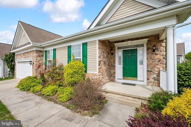 property entrance featuring an attached garage, driveway, and stone siding