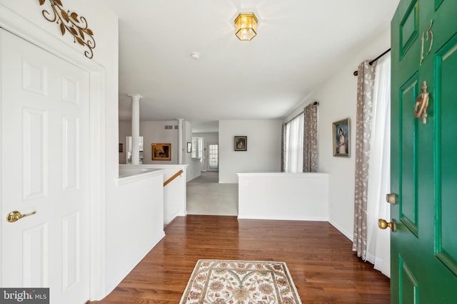 foyer entrance featuring baseboards, dark wood-style floors, and ornate columns