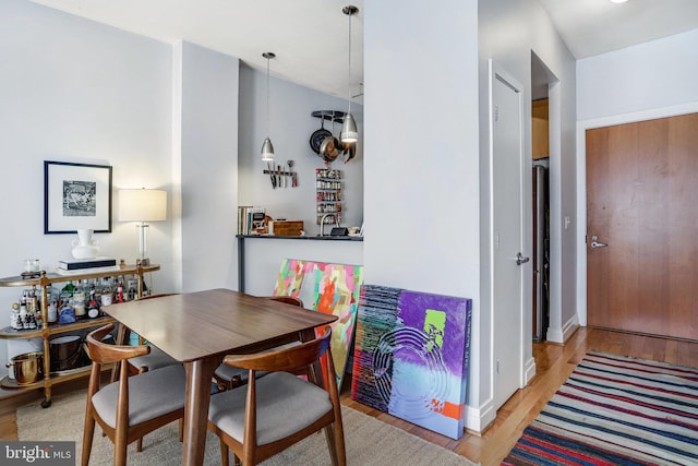 dining room featuring light wood-style floors, baseboards, and vaulted ceiling
