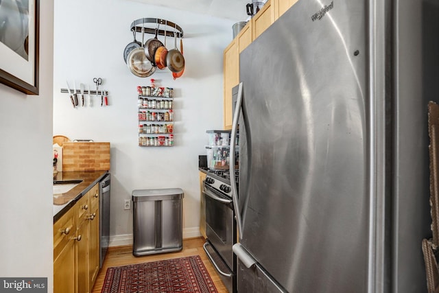 kitchen with stainless steel appliances, tasteful backsplash, light wood-style floors, and dark countertops