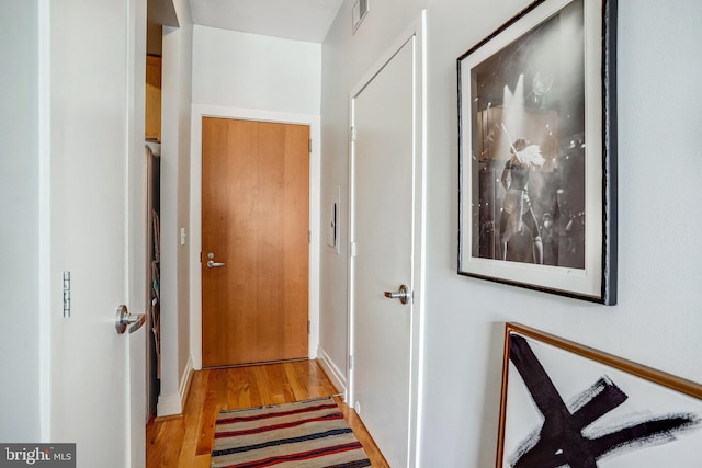 hallway with light wood-style floors, baseboards, and visible vents