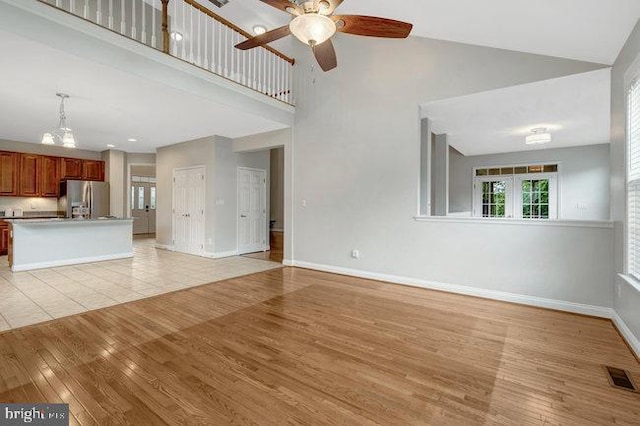 13404 Fieldstone Way, Gainesville, VA 20155 - unfurnished living room featuring ceiling fan, light wood-type flooring, a towering ceiling, and baseboards