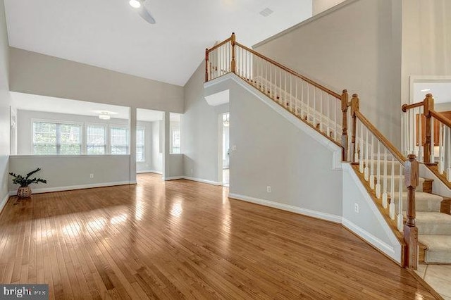 13404 Fieldstone Way, Gainesville, VA 20155 - unfurnished living room featuring hardwood / wood-style floors, high vaulted ceiling, baseboards, and stairway
