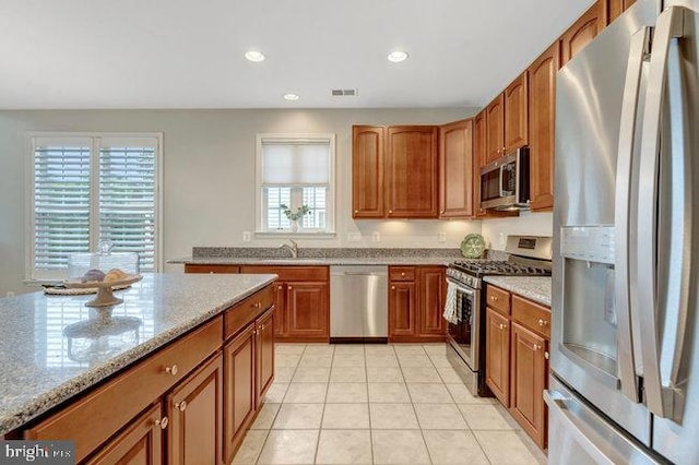 13404 Fieldstone Way, Gainesville, VA 20155 - kitchen with stainless steel appliances, brown cabinets, light stone counters, a sink, and recessed lighting