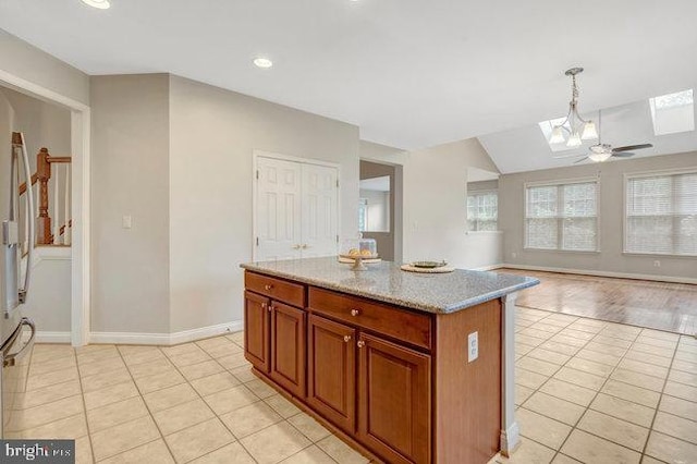13404 Fieldstone Way, Gainesville, VA 20155 - kitchen with a skylight, light tile patterned floors, open floor plan, a kitchen island, and baseboards