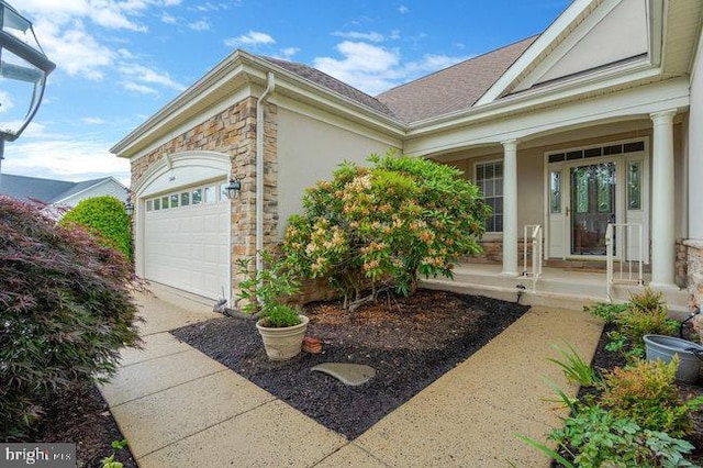 13404 Fieldstone Way, Gainesville, VA 20155 - view of exterior entry with an attached garage, stone siding, covered porch, stucco siding, and concrete driveway