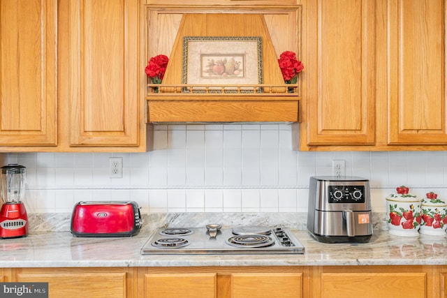 kitchen with decorative backsplash, stainless steel electric cooktop, and light stone countertops